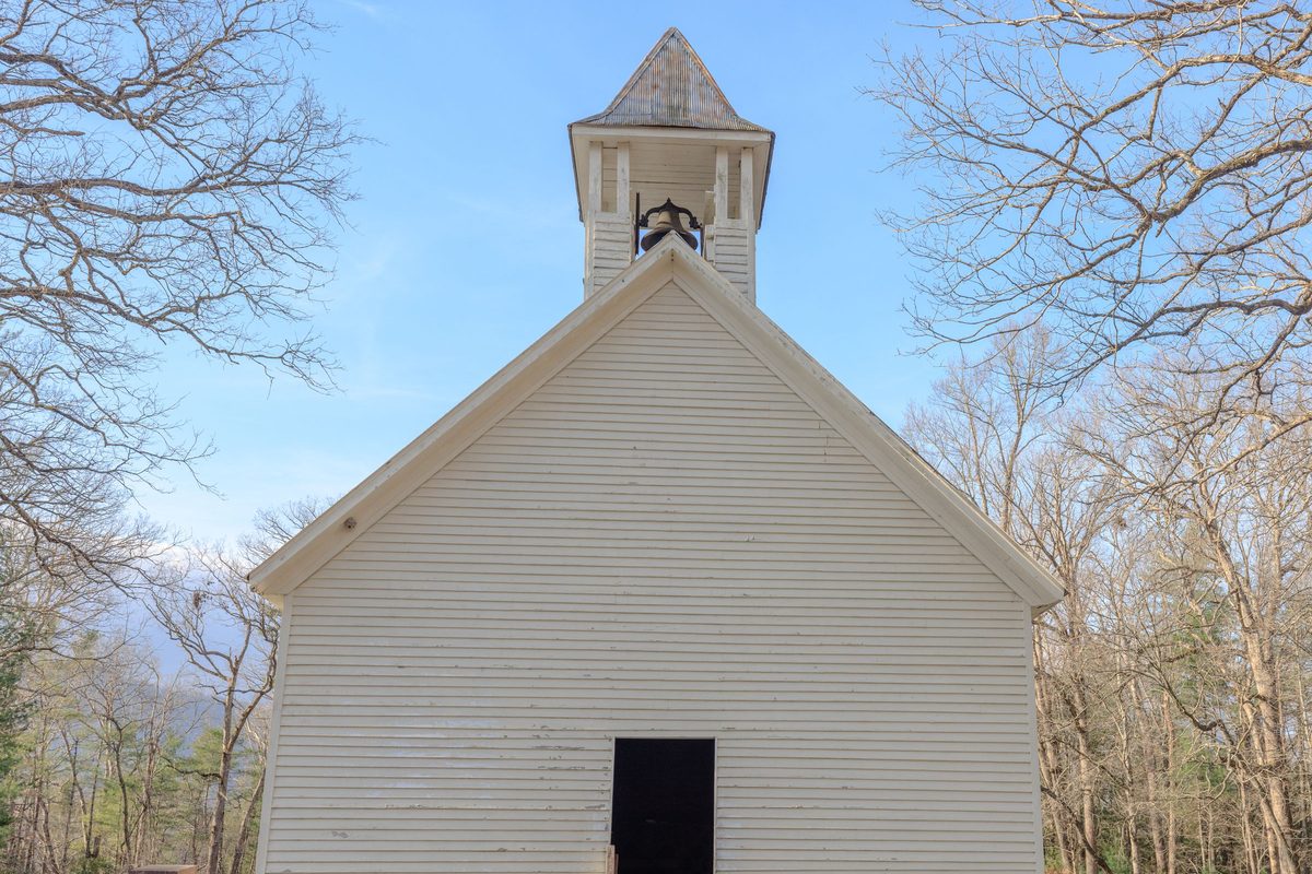 White wooden chapel with a bell cupola among bare trees